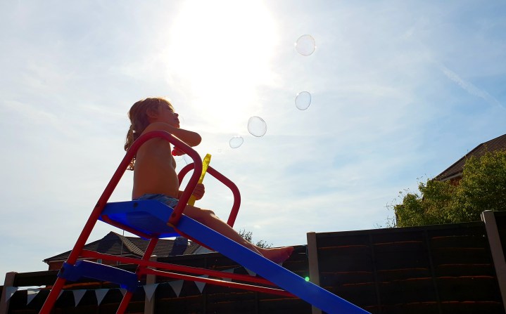Sunny evening. Kid on a slide. Bubbles. 4 freckled faces.