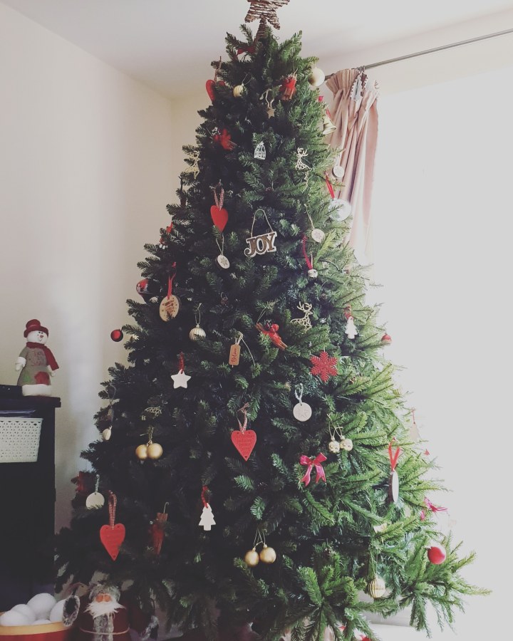 Big Christmas tree with red, white, wooden and gold decorations. 4 Freckled Faces.